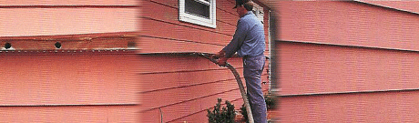Technician performing re-insulation on the exterior of an aluminum-sided home.