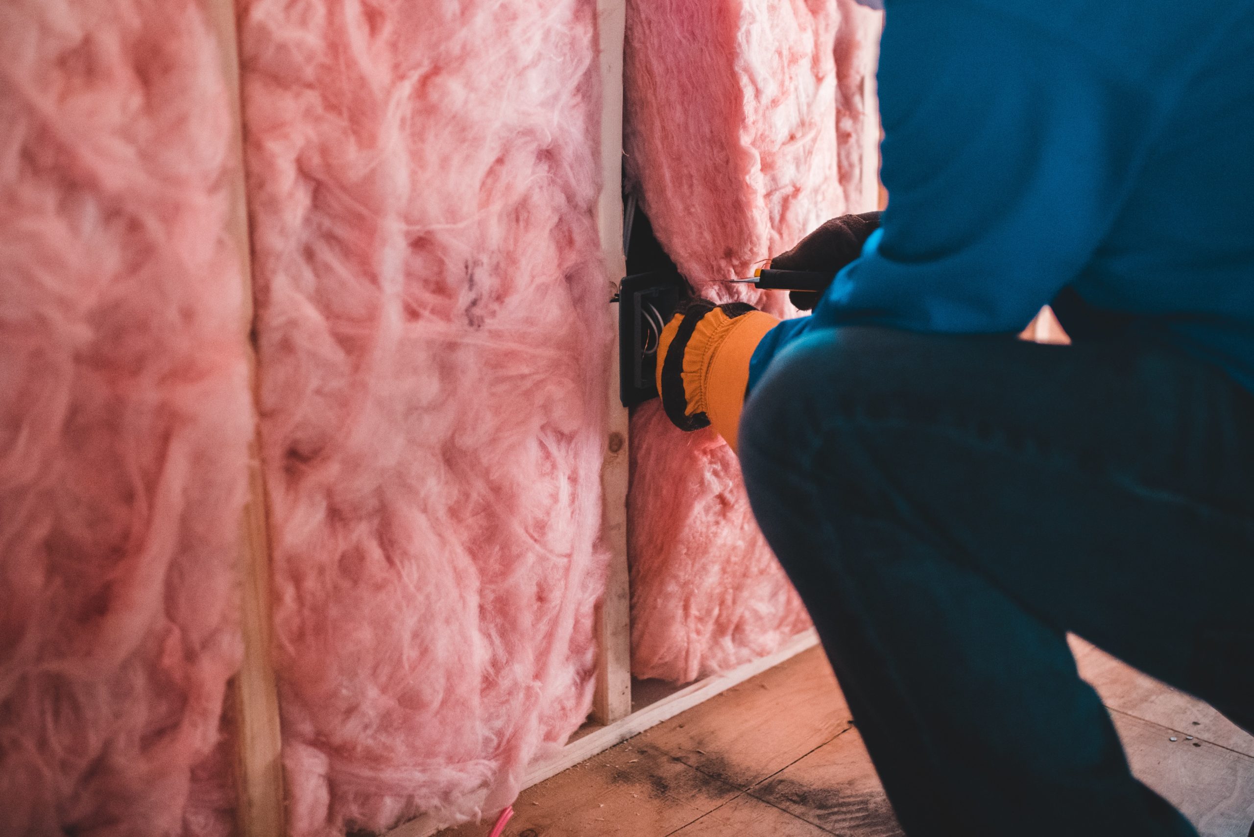 Pink fiberglass batt insulation being installed in a wall.