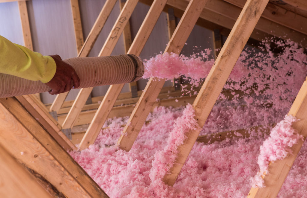 loose-fill fiberglass insulation being installed in attic