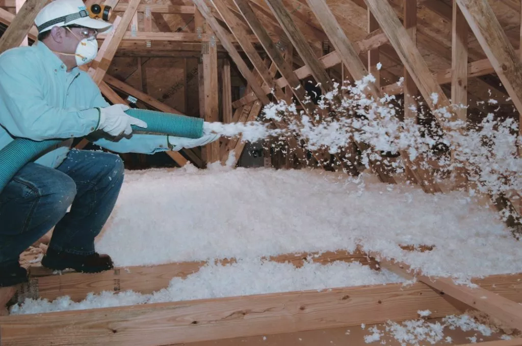 Insulation contractor installing blown-in insulation in an attic.