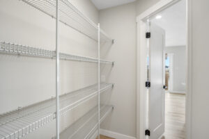 White pantry with a door that is open. The pantry is filled with shelves and has a wire mesh design